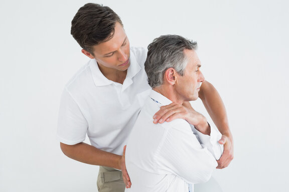Ein Mann mit nicht-spezifischen Rückenschmerzen wird von einem Physiotherapeuten behandelt.